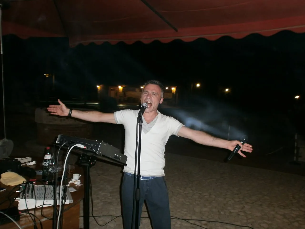 Lello canta a braccia aperte in una serata all'aperto, estate 2013